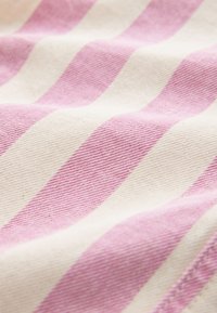 Close-up of soft fabric with alternating wide pink and white diagonal stripes and visible weave texture.