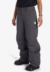 Grå snöbyxor med lös passform, som har en dubbelknäppning, sidofickor och ett logomärke på vänster lår. Strukturerat tyg.