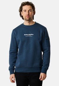 Felpa blu navy realizzata in un tessuto morbido, caratterizzata da un collo a giro, maniche lunghe, un logo frontale e una tasca utility sulla manica sinistra.