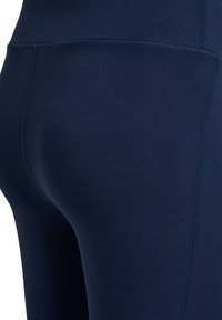 Leggings blu navy con una texture liscia ed elastica, caratterizzate da cuciture tono su tono e un design aderente che segue le forme del corpo.