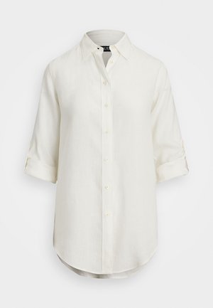 Chemise en lin blanc avec un design à boutons, manches courtes retroussées, col et ourlet arrondi. Présente des boutons de couleur claire.
