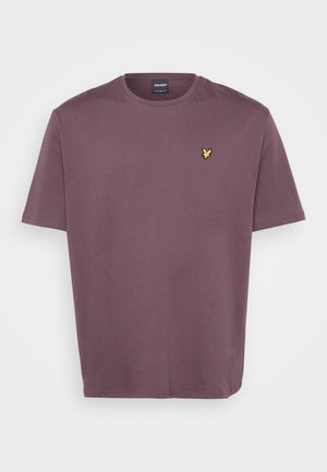 Camiseta de algodón morada con mangas cortas. Presenta un pequeño logotipo amarillo bordado en el lado izquierdo del pecho. Diseño simple, corte relajado.