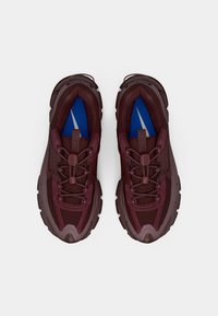 Pantofi sport burghie din material texturat, cu guler căptușit, vârf întărit și branțuri albastre; caracteristici notabile de șnururi proeminente și un design stratificat.