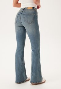 Lichte spijkerbroek met flair, met een gemiddelde taille, vijf zakken en een bruine leren label op de achterste tailleband.