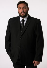 Schwarze Sakk jacket mit tailliertem Schnitt, ausgestattet mit zwei Knöpfen, geschlitzten Revers und einer einzelnen Brusttasche, getragen über einem weißen Hemd und einer schwarzen Krawatte.