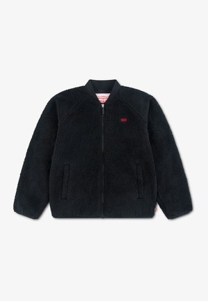 Veste polaire noire zippée avec poches latérales et petit logo rouge Levi's sur la poitrine, présentée sur fond blanc.