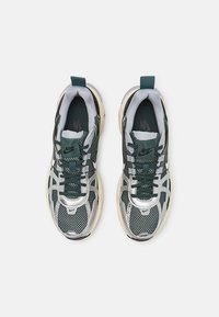 Nike-sneakers med ett överdel i mesh och syntetmaterial, mörkgrön och silverfärgade, texturerad design, samt en vadderad plös med en dragflik.