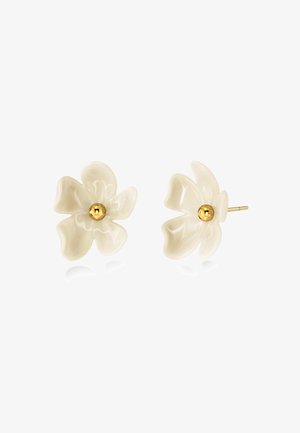 Boucles d’oreilles clous blanches en forme de fleur avec cinq pétales chacune et une petite boule dorée au centre, présentées sur un fond blanc.