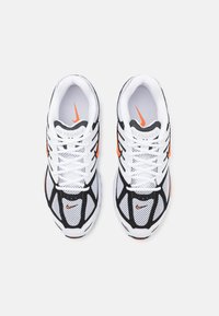 White mesh running shoes with black accents and orange details. Features a lace-up design and textured sole. "Air Pegasus" branding visible.