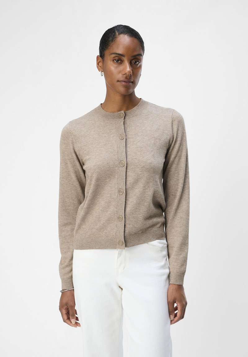 Beige strikket cardigan med rund hals, lange ermer og full knappestenging. Myk tekstur med ribbede detaljer ved kanten og mansjettene.