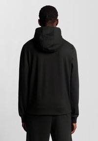 Felpa con cappuccio nera, realizzata in un tessuto liscio ed elastico. Design aderente con polsini e orlo a coste, e un cappuccio di dimensioni medie sul retro.