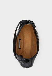 Μαύρη δερμάτινη τσάντα χειρός με απαλή, λεία υφή. Το εσωτερικό είναι καφέ με τσέπη φερμουάρ και ταμπέλα. Σχεδιασμένη με καμπύλη μορφή και κοντό χερούλι.