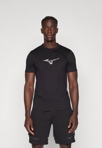 Juodas trumpomis rankovėmis sportinis marškinėlis su pilku Mizuno logotipu ant krūtinės, pagamintas iš lygaus, lengvo audinio.