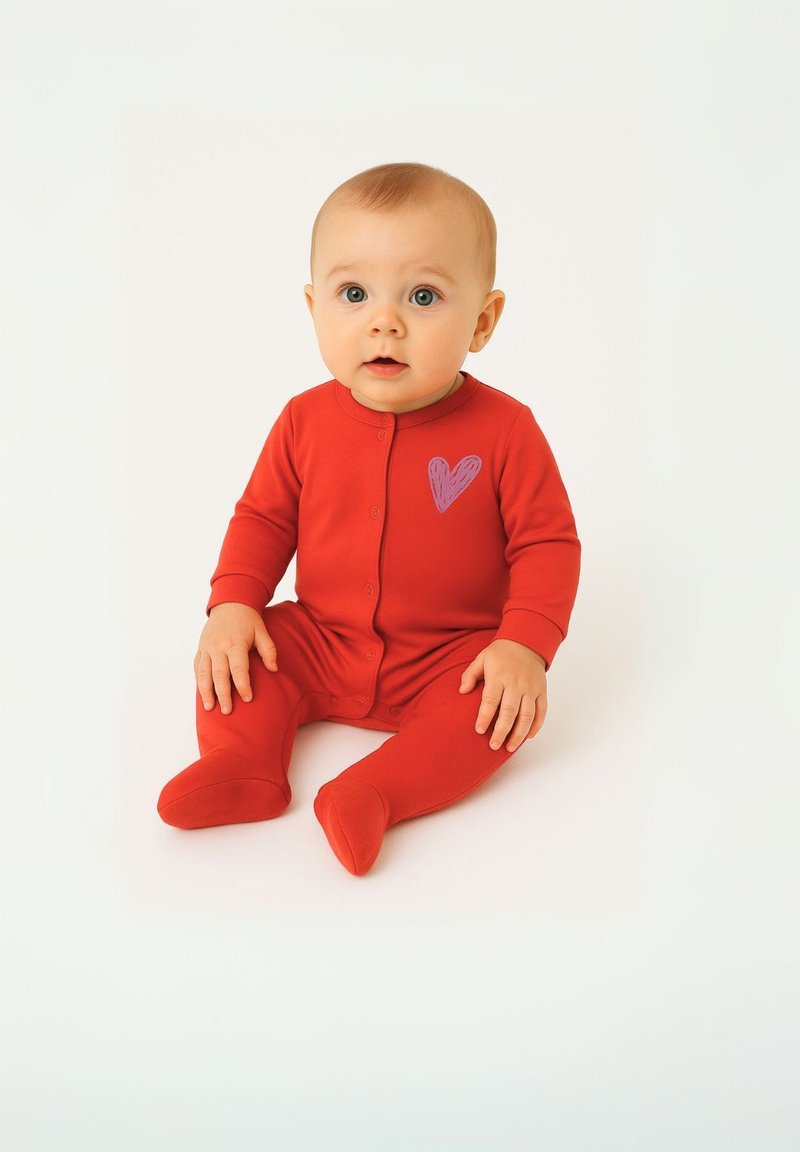 Rød baby-dækkende dragt lavet af blødt stof, med et lilla hjerte-design på venstre bryst. Lange ærmer og fodede ben.