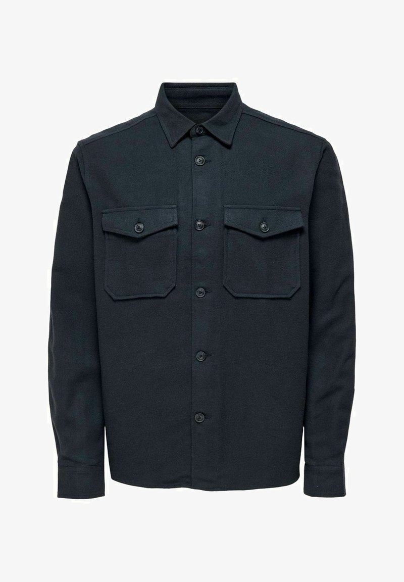 Czarna koszula zapinana na guziki, wykonana z tkaniny o fakturze. Posiada szpiczasty kołnierz, dwie kieszenie na piersi oraz długie rękawy z mankietami na guziki.