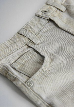 Hele beežid denimist teksad sirge lõikega, esitasku, nähtavate õmblustega ja hõbedase nupuga sulgemine.