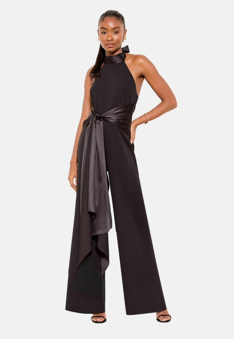 Tuta nera con collo all'americana e cintura di raso. Presenta gambe larghe e dettaglio di tessuto drappeggiato. Tessuto liscio con un design chic.