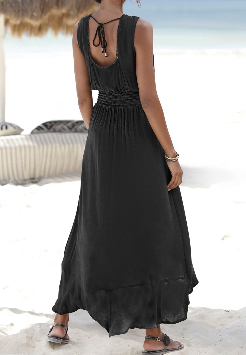 Svart ärmlös maxiklänning med figursydd smockad midja, öppen ryggdesign och flödande nederkant, tillverkad av lättviktsmaterial.