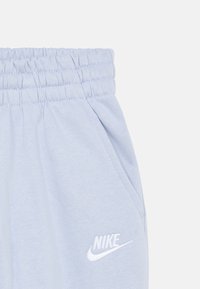 Ανοιχτό μπλε φόρμα με ελαστική μέση, πλαϊνές τσέπες και λευκό λογότυπο Nike στο αριστερό μπούτι. Μαλακή υφή υφάσματος.
