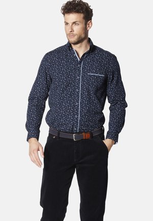 Marineblaue Hemd mit einem kleinen weißen Muster, langen Ärmeln, einem button-down Kragen und einer Brusttasche, kombiniert mit dunklen Hosen und einem Gürtel.