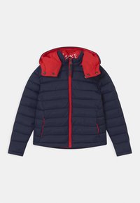 Marineblå polstret jakke med r�ød hætte og lynlås, der har horisontal quiltet tekstur og kontrasterende røde detaljer langs lynlåsen og lommerne.