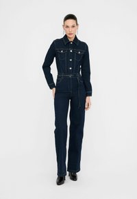 Salopette in denim blu scuro con maniche lunghe, design con colletto, tasche sul petto e vita con cintura. Caratterizzata da gamba dritta e bottoni dorati.
