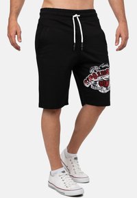 Zwarte katoenen shorts met een elastische tailleband en witte trekkoord, met een kleurrijk logo ontwerp op de linker dij.