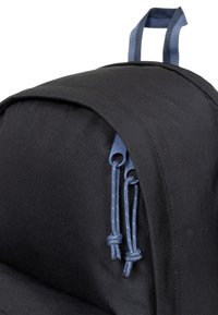 Zaino nero realizzato in tessuto resistente, con un design a forma arrotondata e cordini blu con accessori robusti. Dettagli sulla superficie testurizzata visibili.