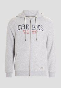 Sudadera con cremallera gris hecha de tela suave, con un diseño en la parte delantera que dice "CREEKS" en azul marino y "Original Desde 1974" en rojo. Incluye cordones.