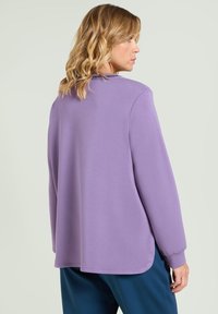 Pullover lavanda a maniche lunghe con vestibilità rilassata, scollo rotondo e polsini a coste; presenta un orlo curvo e una trama liscia.
