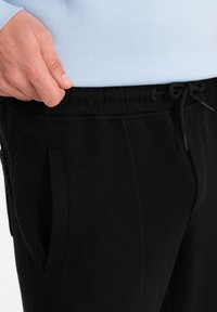 Zwarte sweatpants met een elastische tailleband met trekkoord, zijzakken en een gestructureerde stofafwerking.