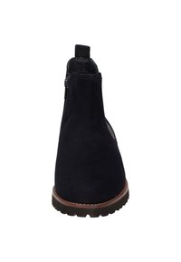Stivale alla caviglia in suede blu navy con una texture liscia, zip sul retro, pannelli laterali elastici e suola in gomma testurizzata. Cuciture marroni contornano la suola.