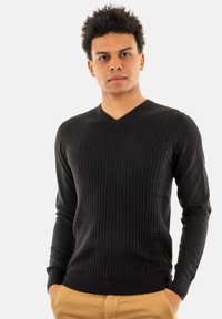 Maglione nero a maniche lunghe con scollo a V, design a coste testurizzate, silhouette aderente e polsini e orlo a coste.
