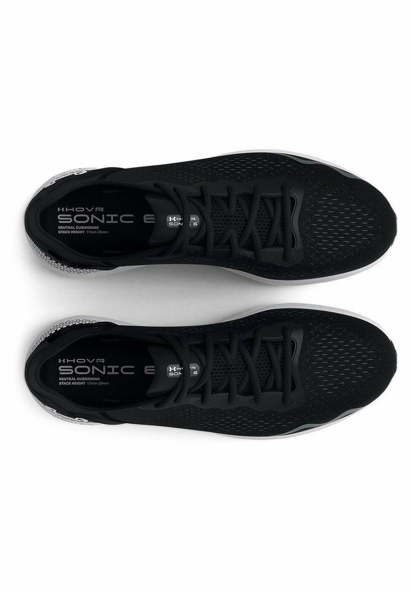 Baskets de sport noires avec une tige en mesh, des détails texturés, des lacets plats et une semelle blanche, avec la marque "HOVR SONIC 6" à l'intérieur.