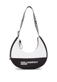 Peties krepšys, pagamintas iš lygaus balto ir juodo audinio, turintis pusmėnulio formą, reguliuojamą diržą su prekės ženklu ir viršutinį užtrauktuką.