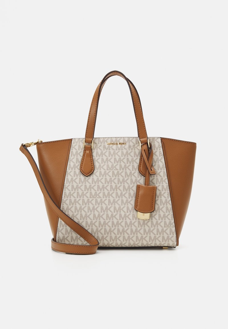 Sac à main beige et marron clair avec deux petites poignées et une longue bandoulière, présentant un motif de logo et une petite étiquette attachée.
