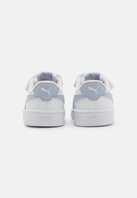 Baskets blanches avec des accents lavande, en matériau texturé, avec un col rembourré et des sangles réglables. Présente un logo sur le talon et la semelle.
