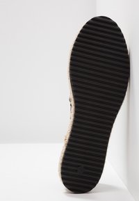 Semelle en caoutchouc avec des rainures horizontales, accent en jute naturel sur les côtés, schéma de couleurs noir et beige clair, design plat et large.