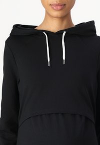 Černá zkrácená mikina z měkké bavlny, s kapucí na šňůrku a žebrovaným spodním lemem. Hladká textura s volným střihem.