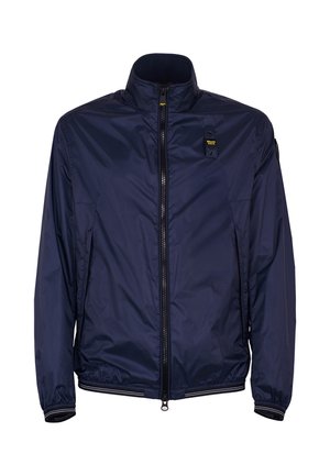 Marineblauwe lichtgewicht jas met rits, opstaande kraag, elastische manchetten en zoom, en een klein gebrandmerkt patch op de linkerborst.