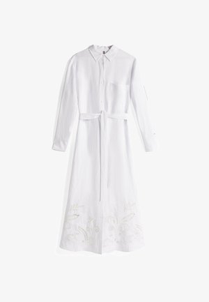 Witte linnen jurk met lange mouwen. Voorzien van een kraag, een borstzak, een tailleband en een ingewikkelde bloemenborduursel aan de zoom.