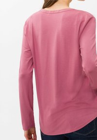 Langärmliges Shirt aus weichem rosafarbenem Stoff, mit Rundhalsausschnitt und abgerundetem Saum, einer glatten Textur und minimalen Design-Details.