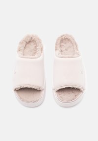Zapatillas deslizantes blancas con un forro de peluche de piel sintética y diseño de dedo abierto. Material superior suave con un sutil logotipo en el lateral.