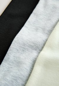 Tri presavijena komada rebraste tkanine u crnoj, svijetlosivoj i krem boji, usko složena jedan uz drugi.