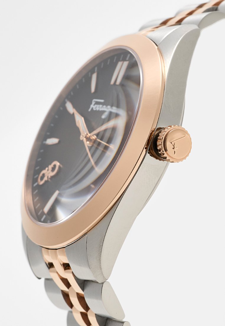 Reloj de plata y oro rosa con un dial negro, caja de acero inoxidable y un acabado suave. Las características incluyen una función de fecha y una corona texturizada.