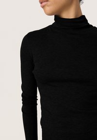 Juodas golfo megztinis, prigludęs dizainas, ilgomis rankovėmis, švelni tekstūra, be siūlių kaklas, minimalūs siuvimo detalės, kūną glostanti siluetas.