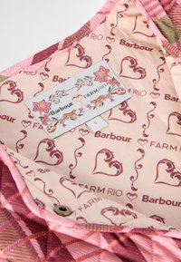 Tecido acolchoado em tons de rosa com padrões geométricos. O interior apresenta uma estampa floral com as etiquetas da marca "Barbour" e "FARM RIO."