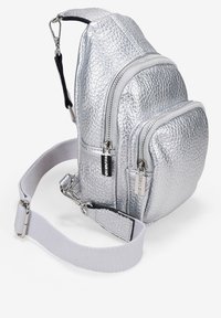 Mochila metálica plateada fabricada con material texturizado. Cuenta con dos bolsillos frontales con cierre, correa ajustable y un diseño elegante.