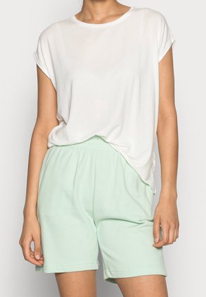 T-shirt blanc à manches courtes associé à un short vert menthe à taille élastique. Le t-shirt est ample et le short a une coupe décontractée.