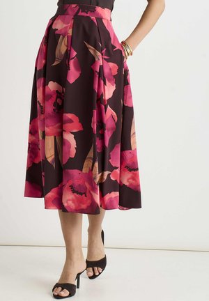 Mid-length skirt with large pink and red floral print, worn with black heeled open-toe sandals and gold bangles on the wrist.